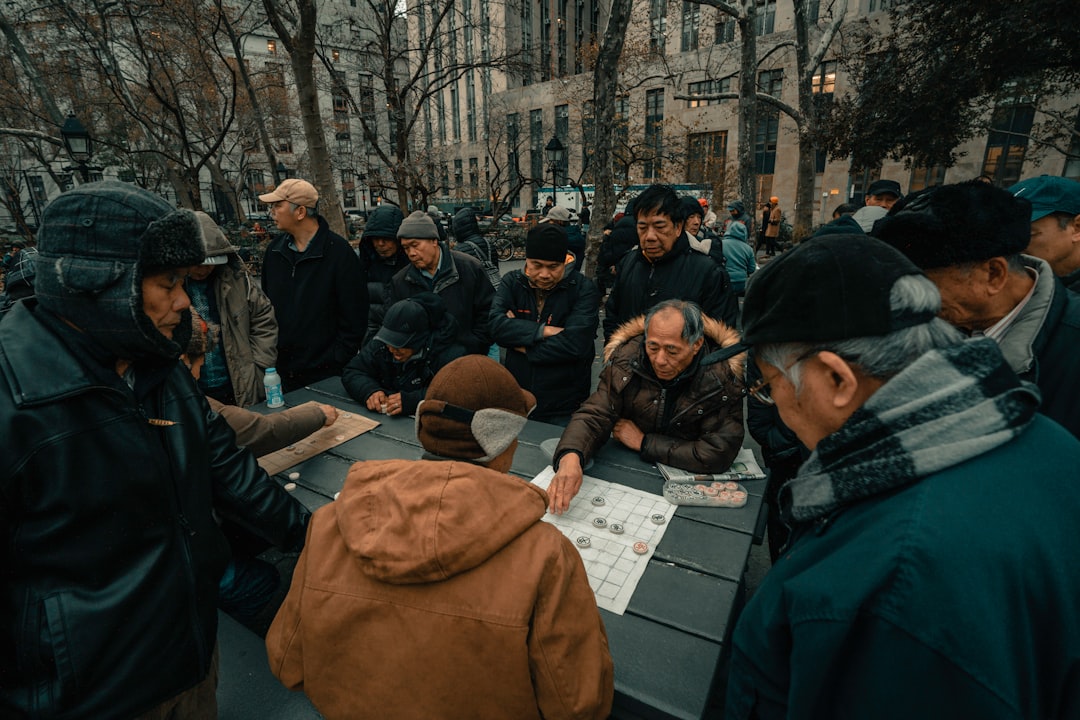A diverse group of professionals and community members gathered around a table, collaborating and pointing at architectural blueprints for a neighborhood plan.