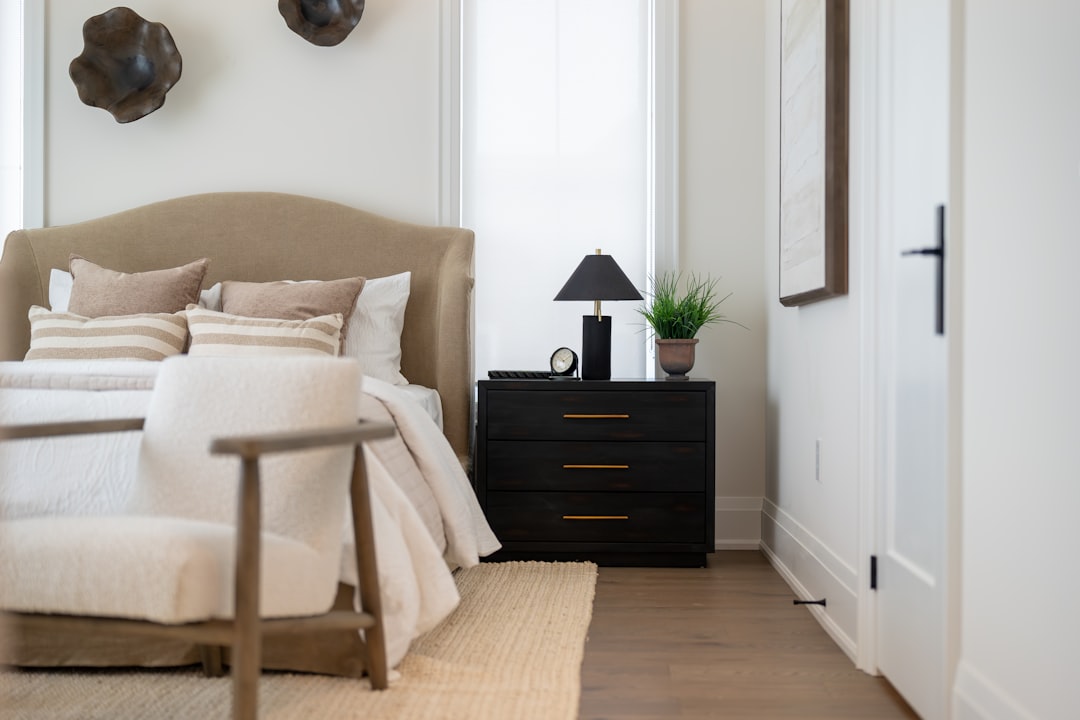 A person with meticulous attention to detail making a perfect bed in a bright, modern bedroom of a luxury short-term rental.