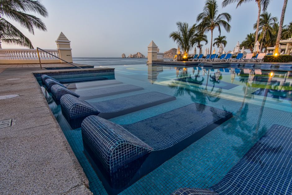 Stunning luxury villa with an infinity pool overlooking the bright blue Sea of Cortez in Cabo San Lucas on a sunny day.