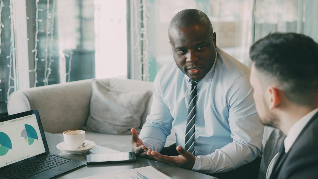 A real estate agent and a client sit across from each other at a modern table, engaged in a professional discussion, representing transparent commission negotiations.